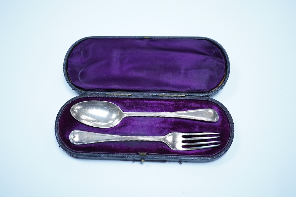 A pair of George V silver mounted dwarf candlesticks, Birmingham, 1920, height 86mm (a.f.), together with a cased Victorian silver beaded Old English pattern christening knife and fork, George Adams, London, 1881.